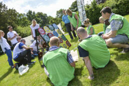Two teams wearing bibs sat down in a sunny field working out the mathematical challenge of 264