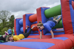Two women falling through an assault course obstacle for 'It's a Knockout!'