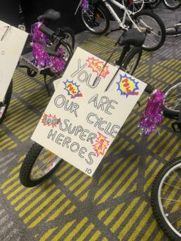 A bike for charity with a poster attached which reads 'you are our cycle superheroes'