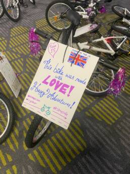 A bike for charity with a colorful poster on it which reads 'This bike was make with love! Happy adventures!'