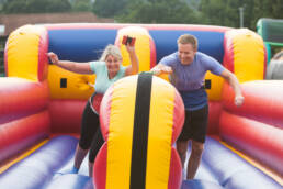 Two people from separate teams battling it out in a It's A Knockout Bungee Run