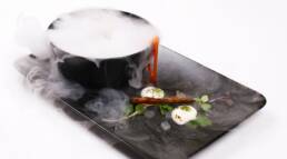Molecular Gastronomy, dry ice. Bowl of Noodles next to a bed of garnish on a rectangular plate