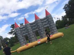 An inflatable castle outdoors with a banner behind it