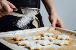 A chef dusting icing over some star shaped biscuits as part of a demonstration